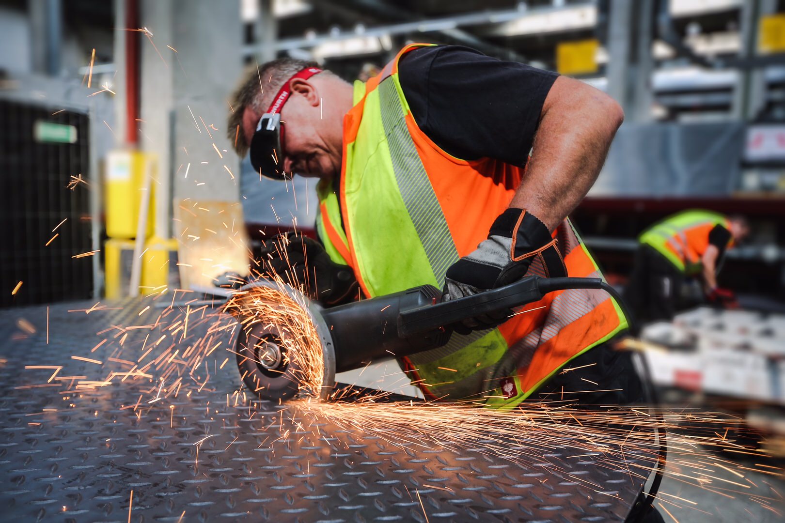 Monteur trennt mit dem Winkelschleifer ein Stahlprofil bei der Industriemontage